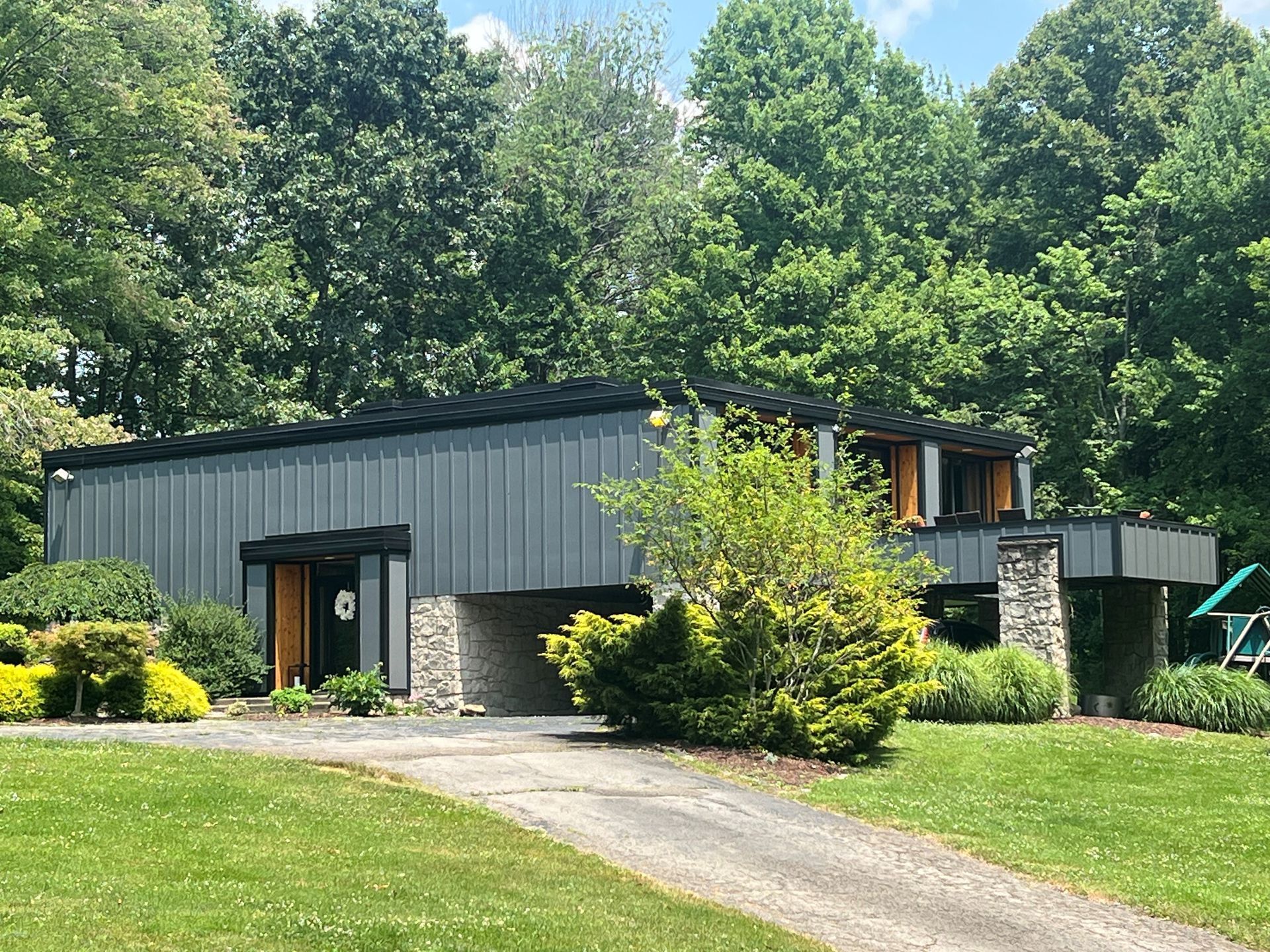 A large house with a driveway leading to it is surrounded by trees