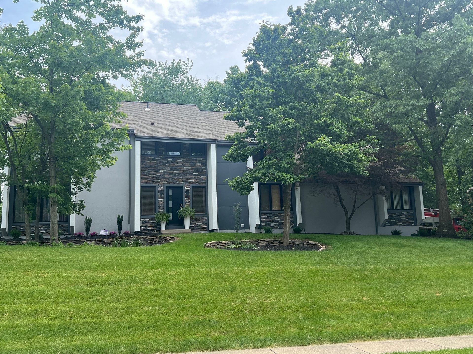 A large house with a large lawn in front of it surrounded by trees.