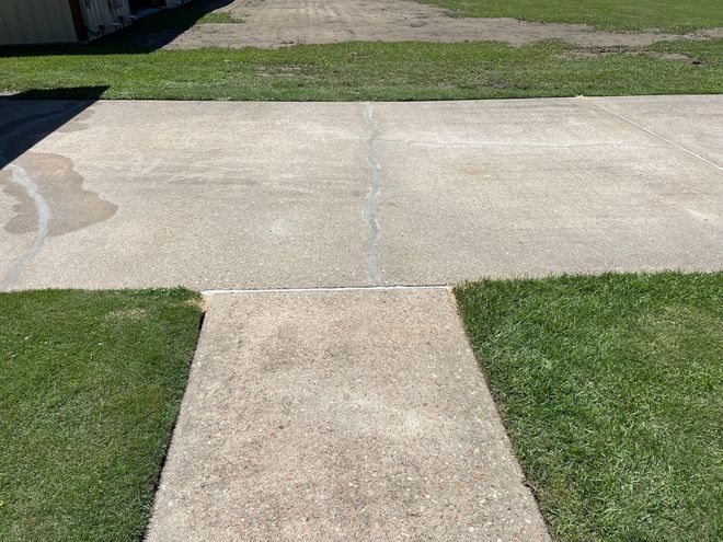 Concrete sidewalk leading from grass area.