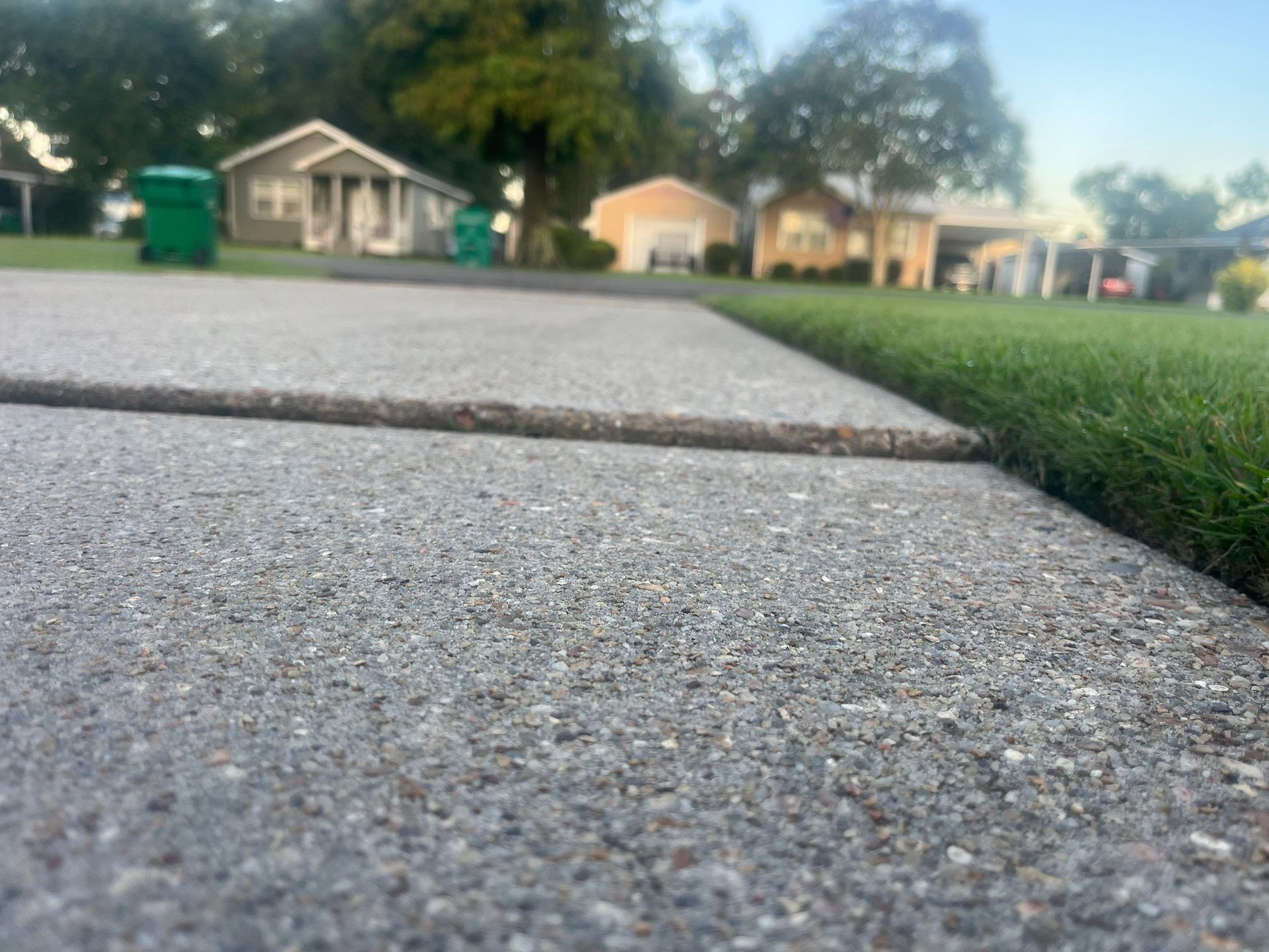 Close-up of a concrete sidewalk next to green grass in a suburban neighborhood.