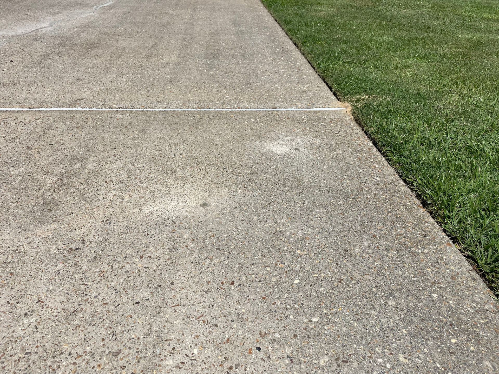 Concrete sidewalk next to green grass.