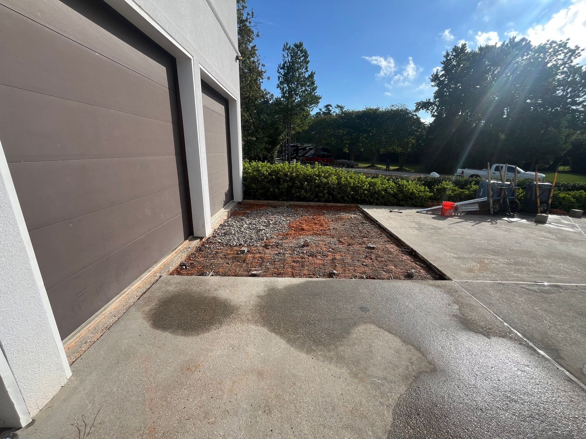 Garage doors and a landscaped area with rocks and mulch in front of a house.