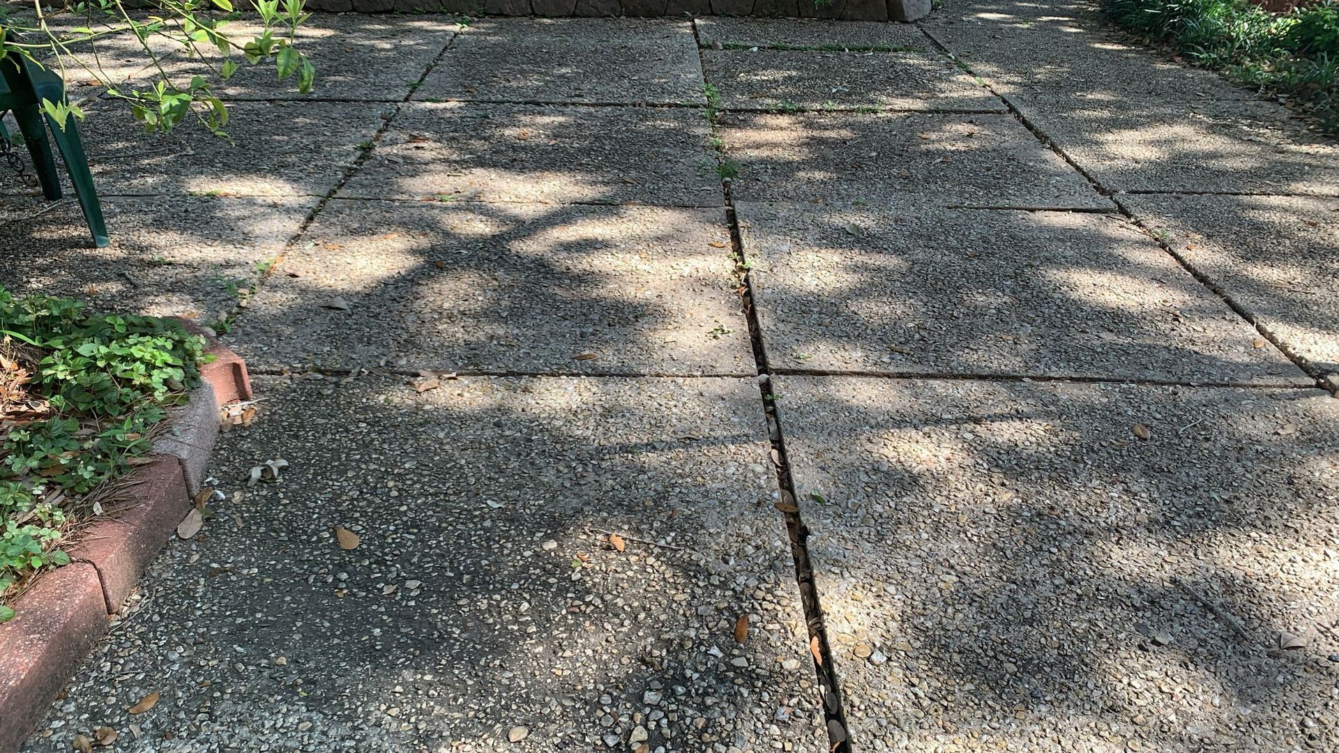 Concrete patio with pebble finish; shadows from trees.