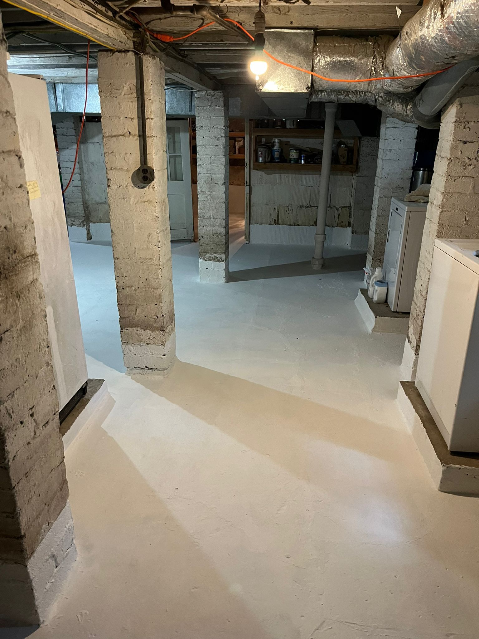 Basement interior with painted cement floor and brick support columns.