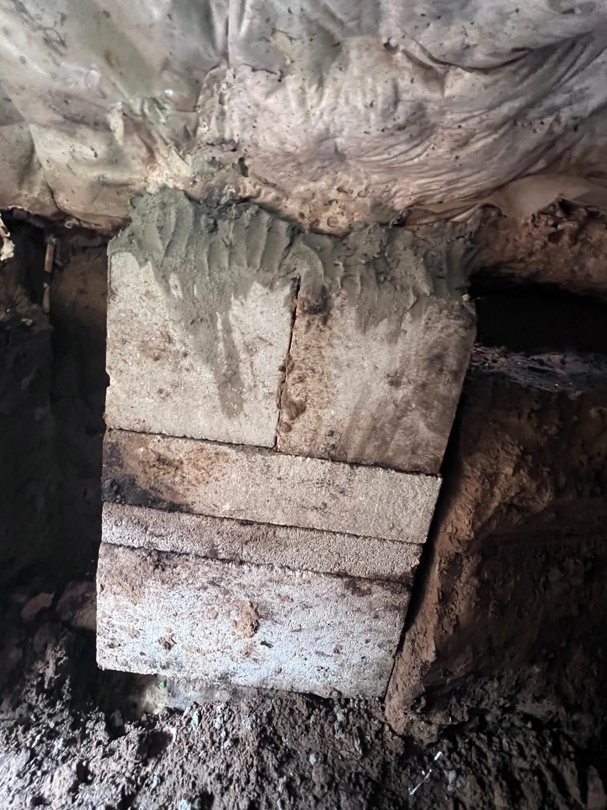 Stone blocks stacked and mortared, supporting a cave ceiling.