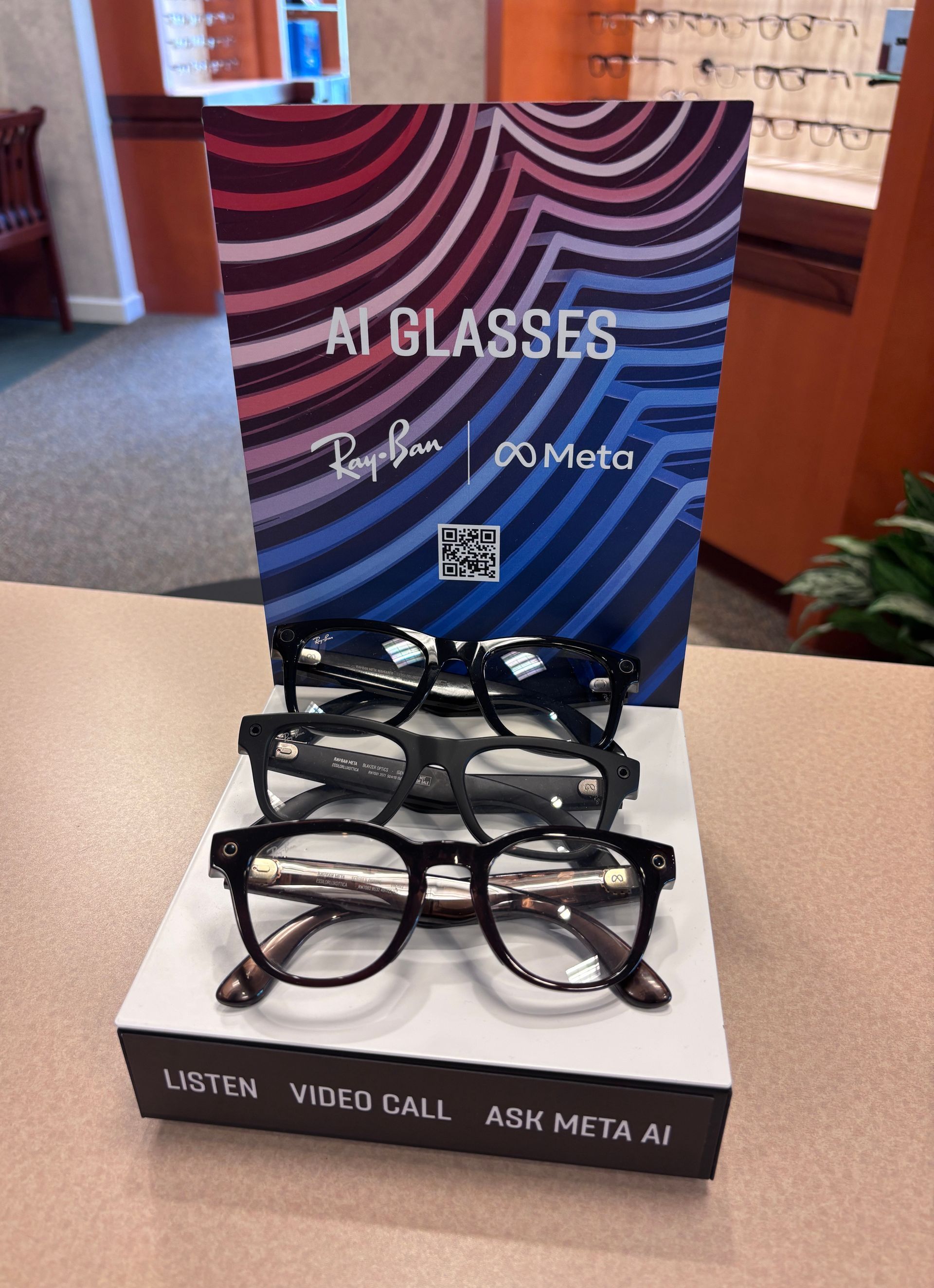 Display of eyeglasses on a counter with a colorful promotional sign behind them