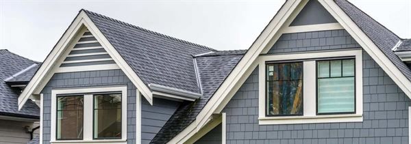 A row of houses with a gray roof and white trim.