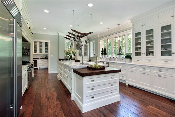 A large kitchen with white cabinets and hardwood floors and stainless steel appliances.