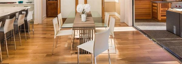A dining room with a glass table and white chairs.