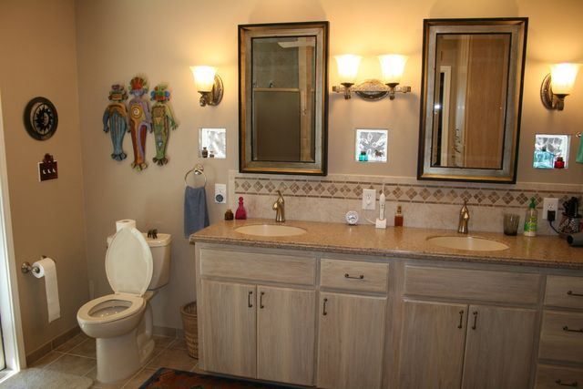 A bathroom with two sinks , a toilet , and two mirrors.