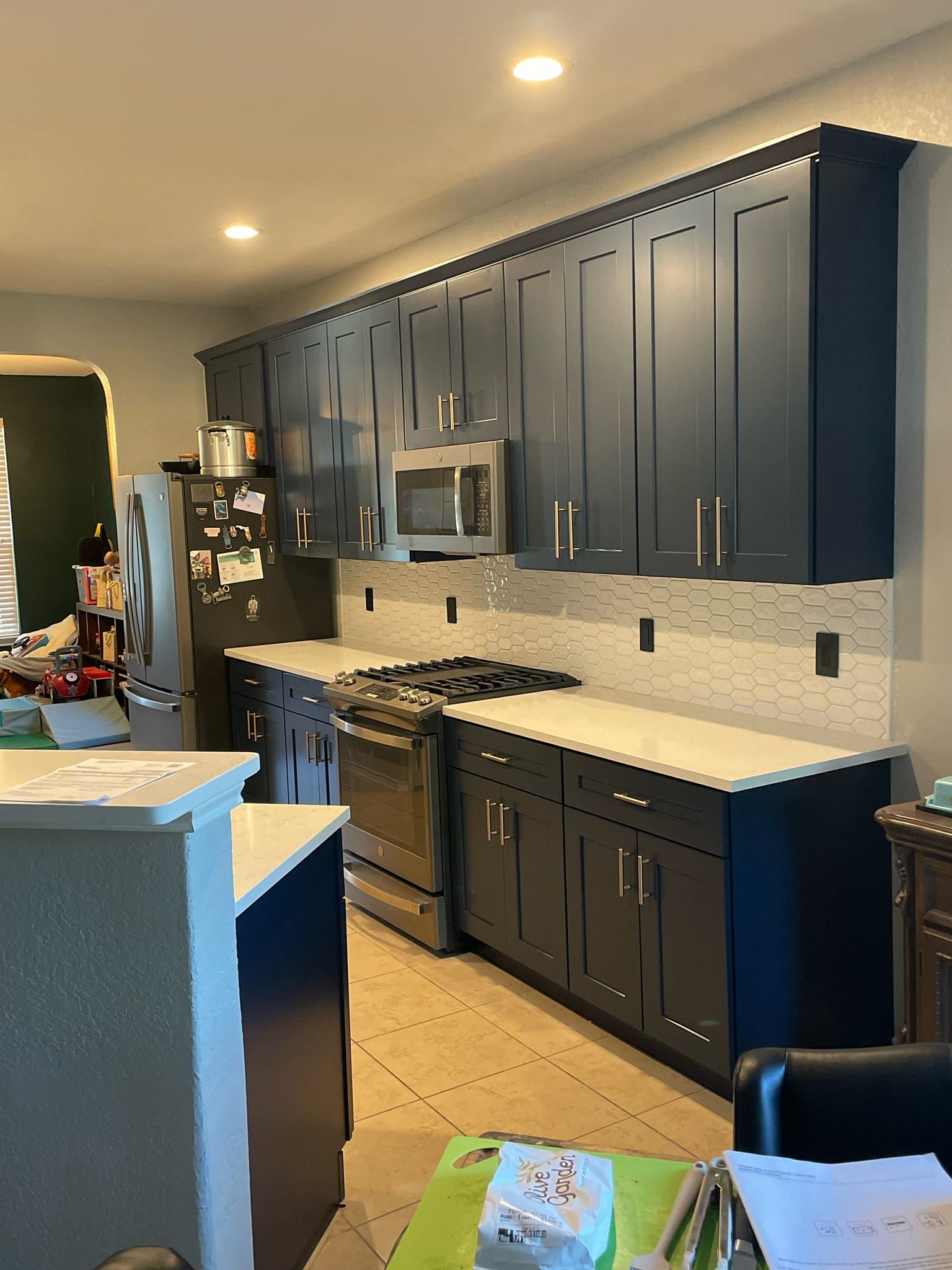 A kitchen with blue cabinets , a stove , a refrigerator , and a microwave.