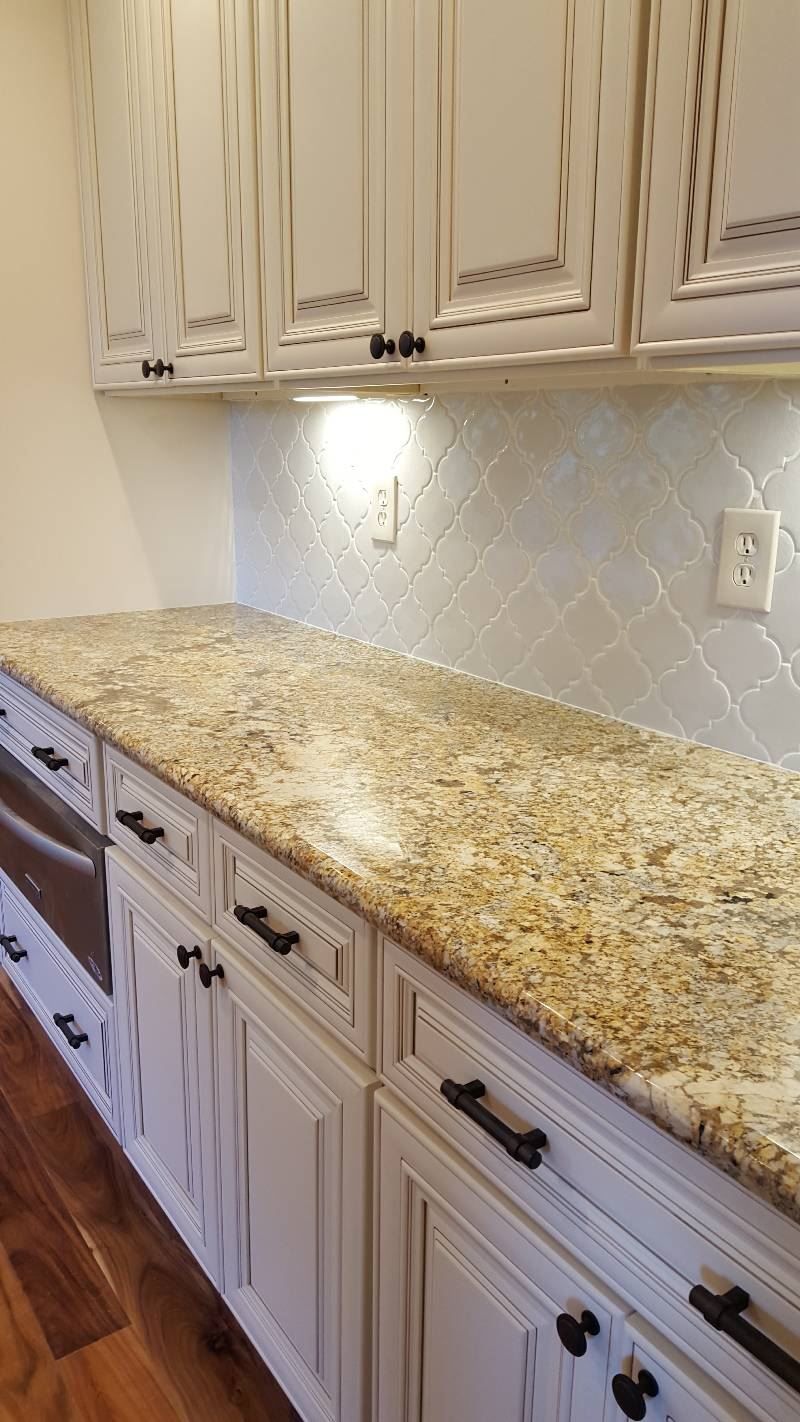 A kitchen with white cabinets and granite counter tops.
