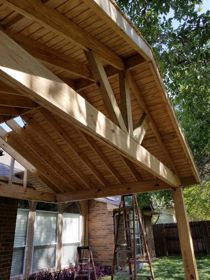 A wooden structure is being built in the backyard of a house.