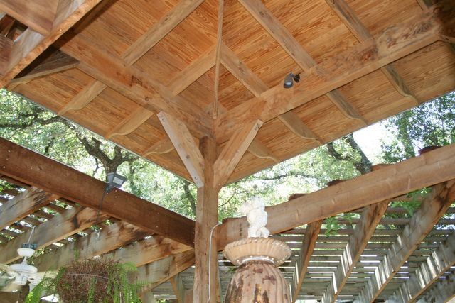A wooden gazebo with a lantern hanging from the ceiling.