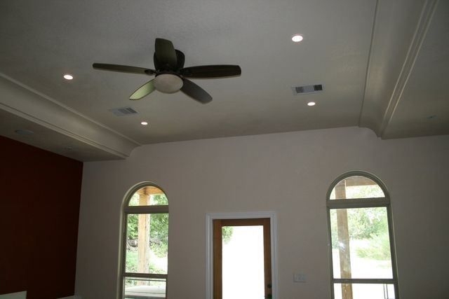 An empty room with arched windows and a ceiling fan