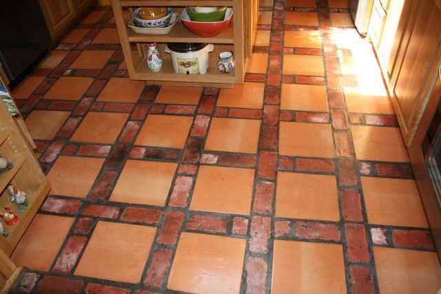 A kitchen with a brick floor and a shelf with bowls on it