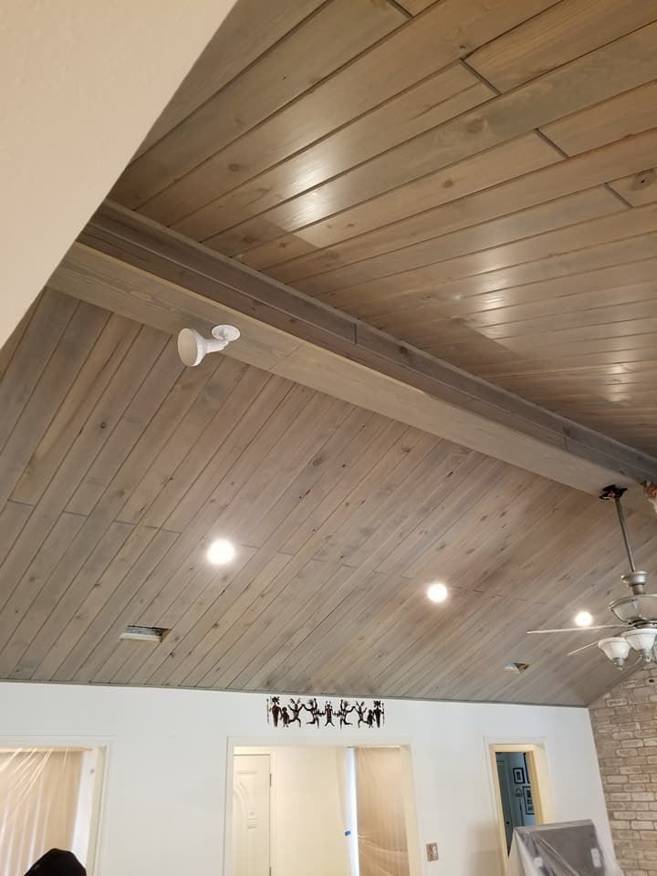 A living room with a wooden ceiling and a ceiling fan.