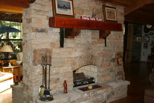 A stone fireplace with a wooden mantle in a living room