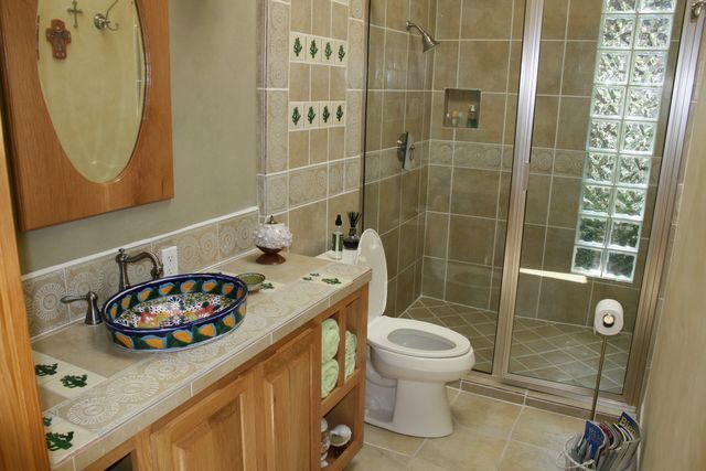 A bathroom with a toilet , sink , mirror and walk in shower.