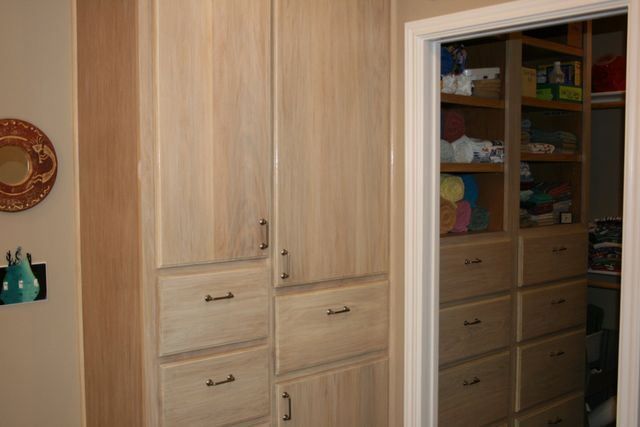 A closet with lots of drawers and cabinets and a mirror on the wall.