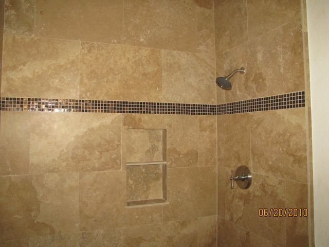 A bathroom shower with a tiled wall and a shower head