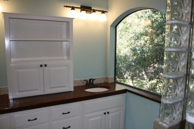 A bathroom with white cabinets and a large window
