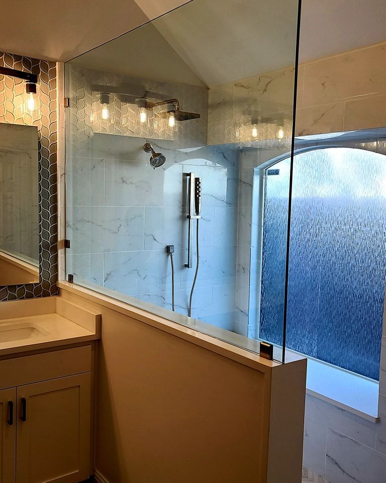 A bathroom with a glass shower door and a sink.