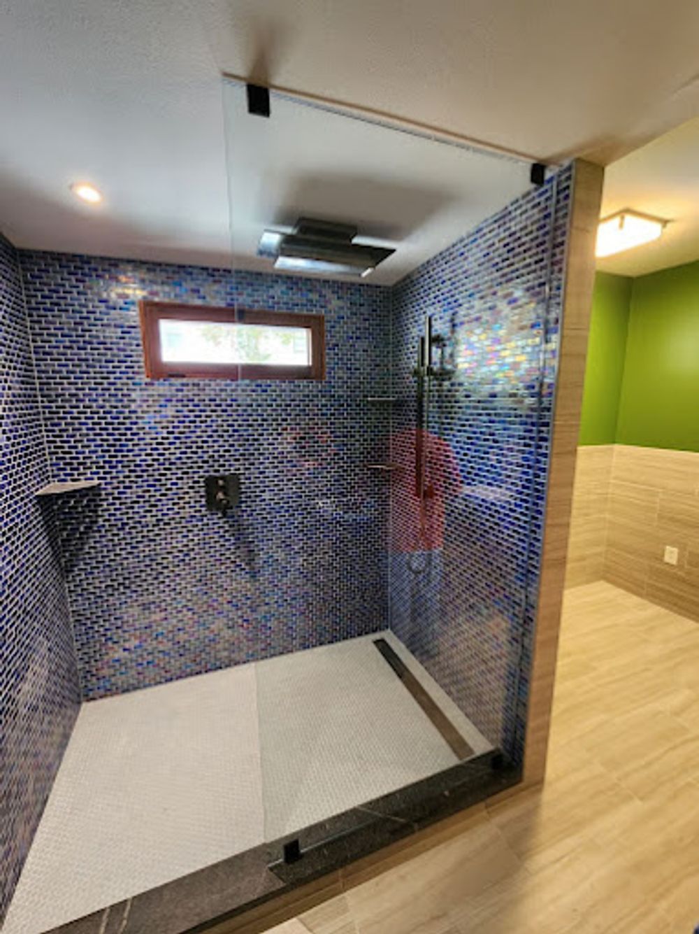 A bathroom with a walk in shower and a window.