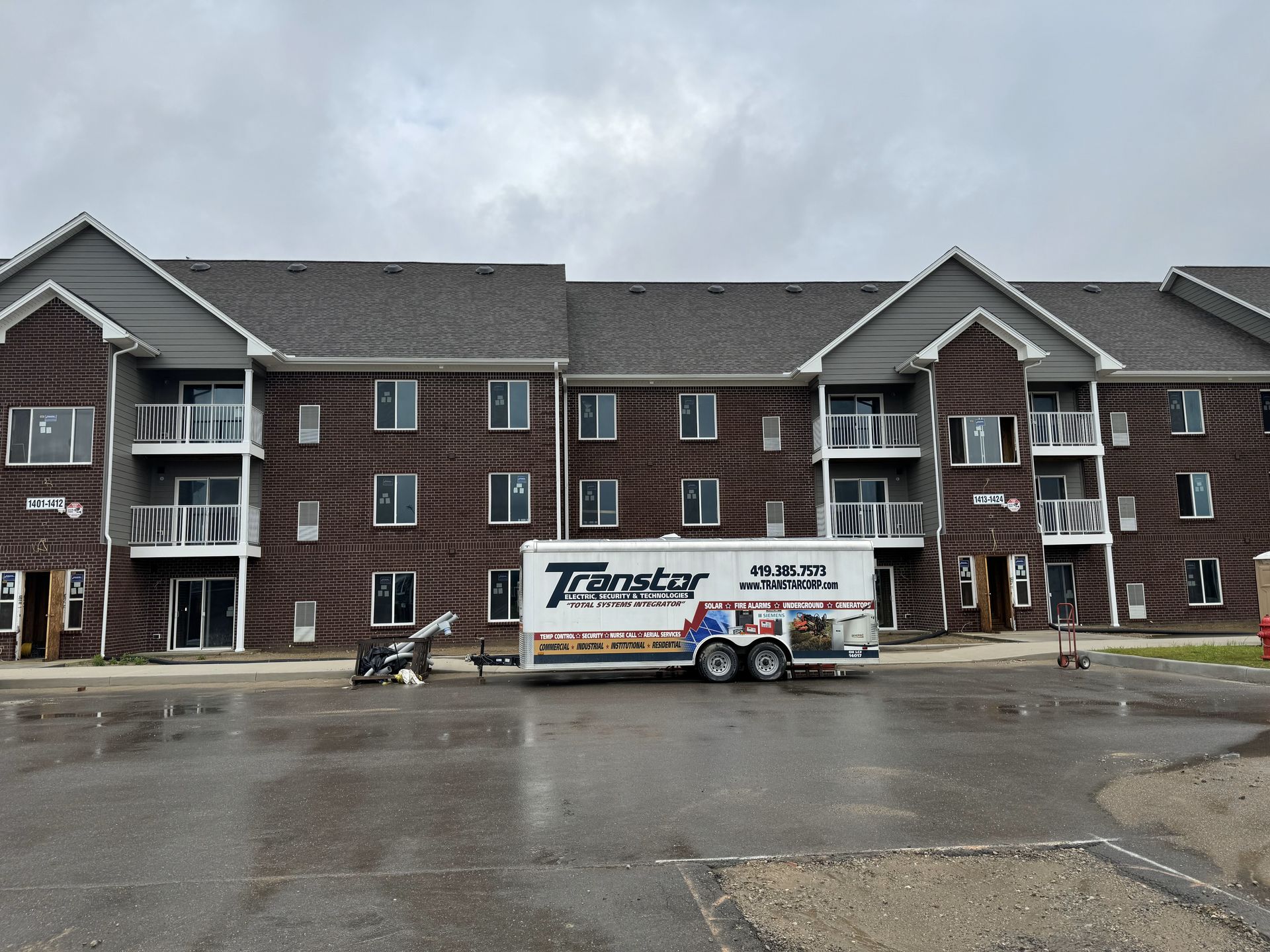 A moving truck is parked in front of a brick apartment building