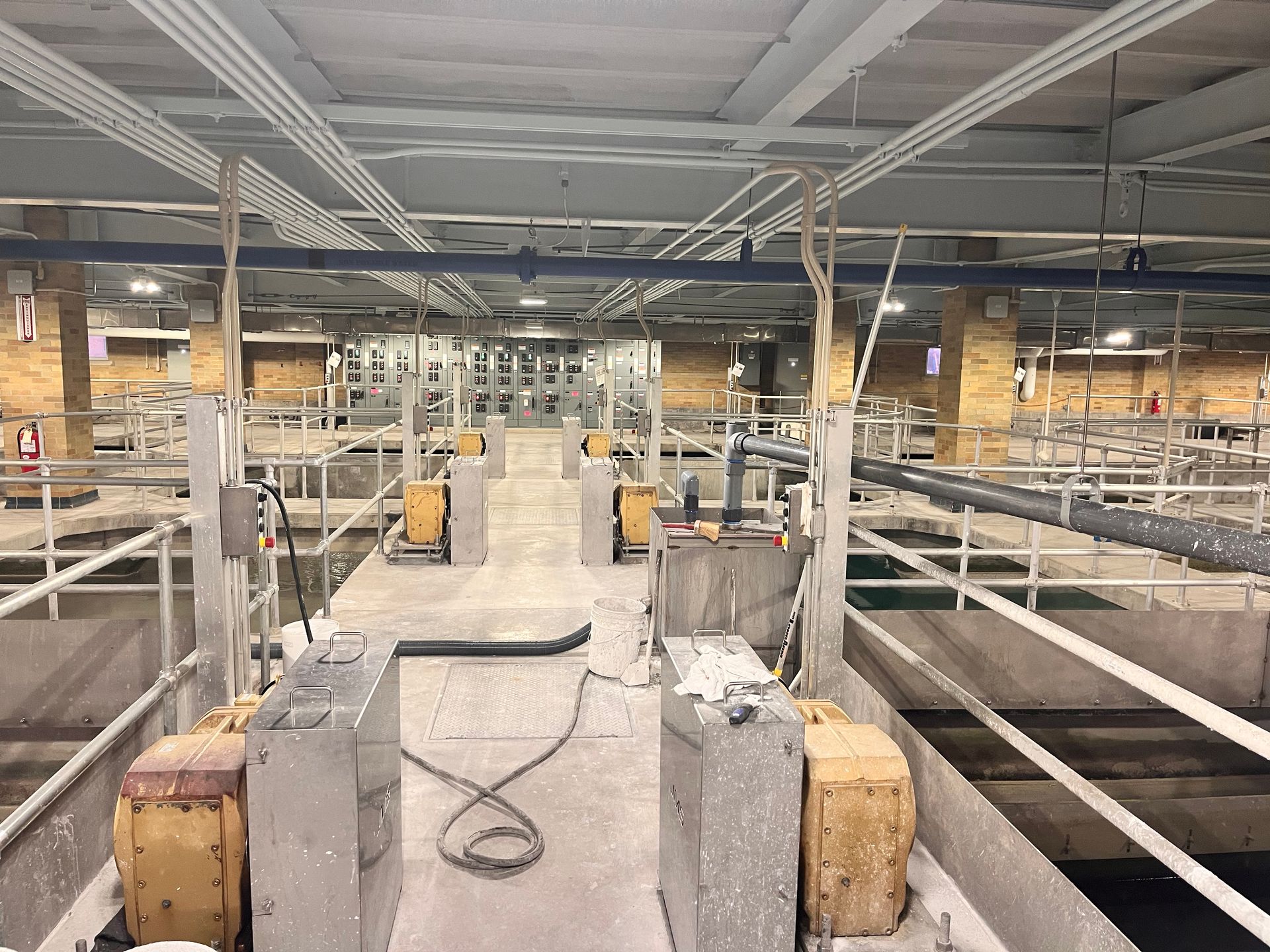 Interior of a wastewater treatment facility with equipment and tanks. Concrete and metal dominate the industrial setting.