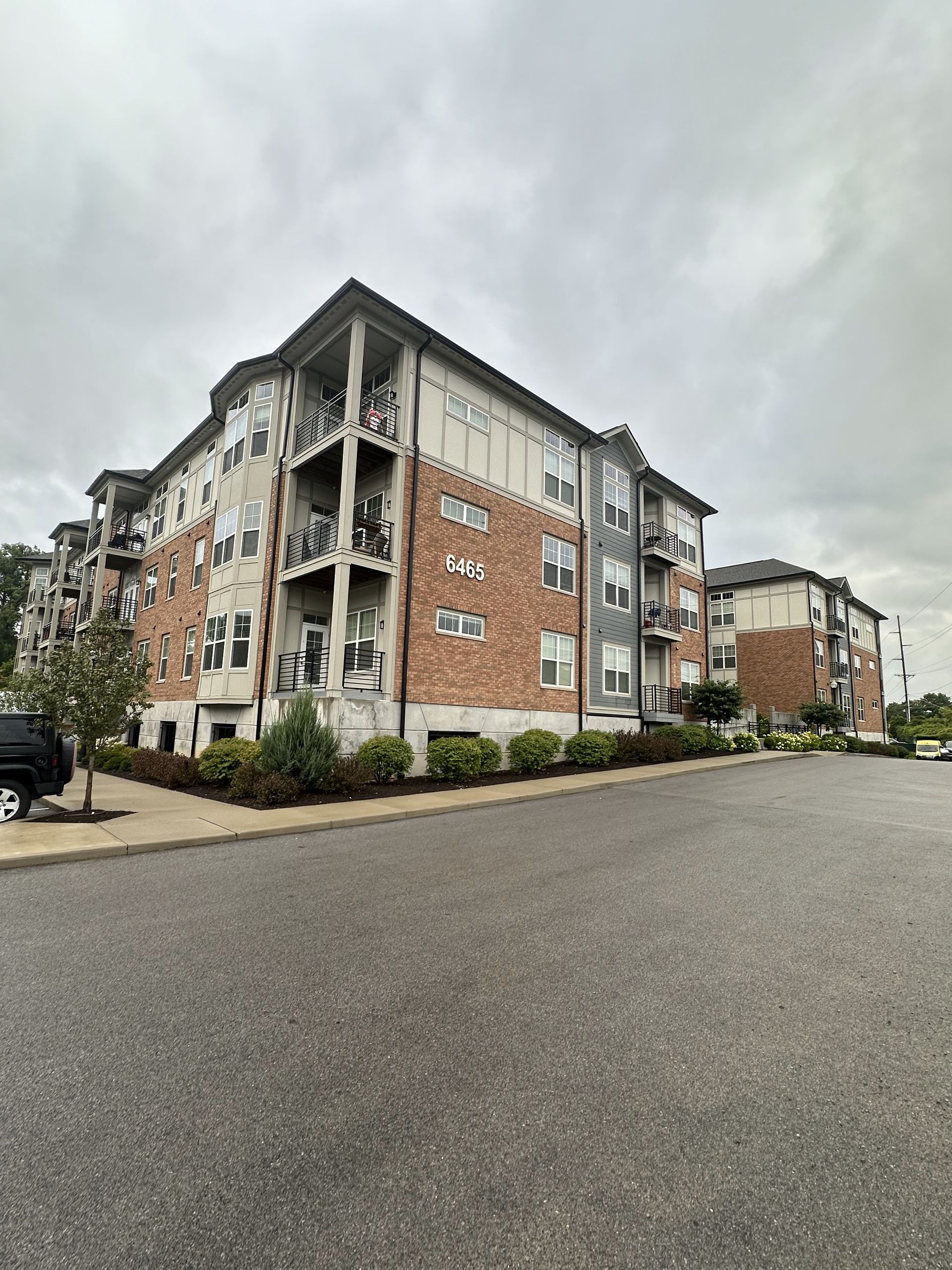 Apartment building with brick and gray exterior on a cloudy day.