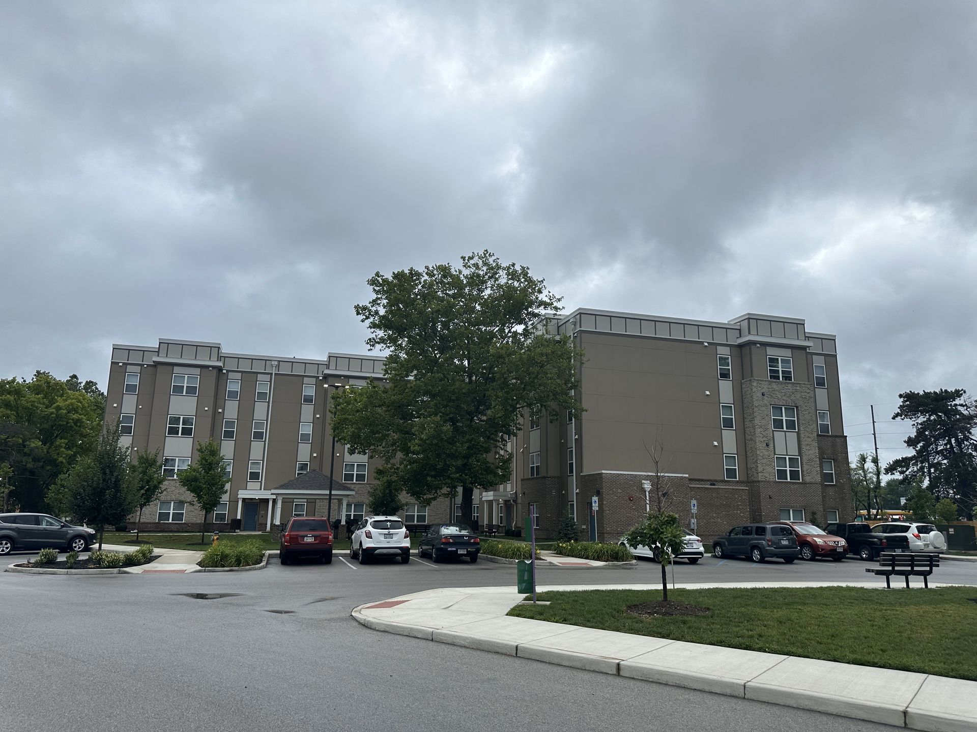 Multi-story apartment building with parked cars on a cloudy day.