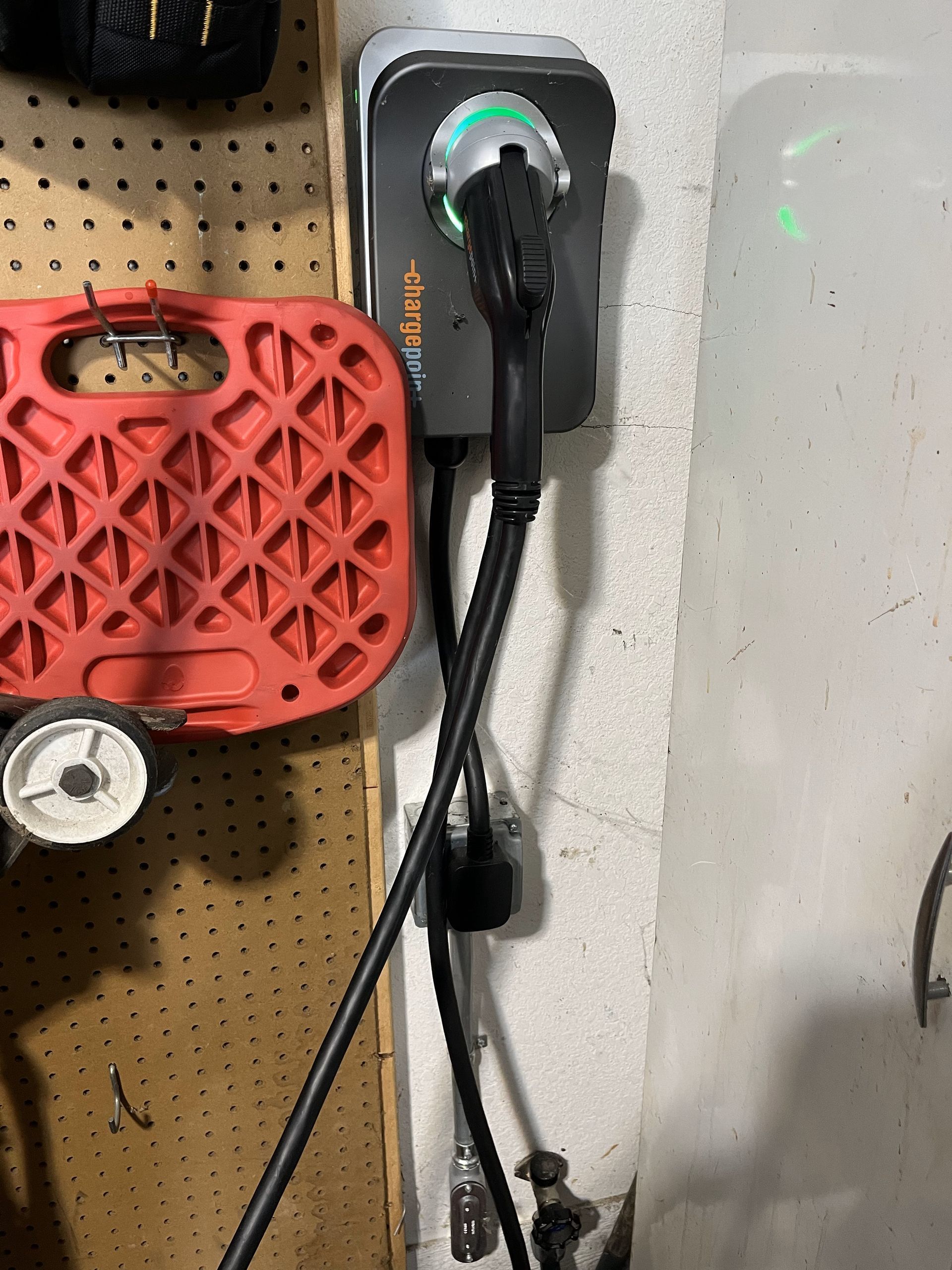 A charger is plugged into a wall next to a red toolbox.
