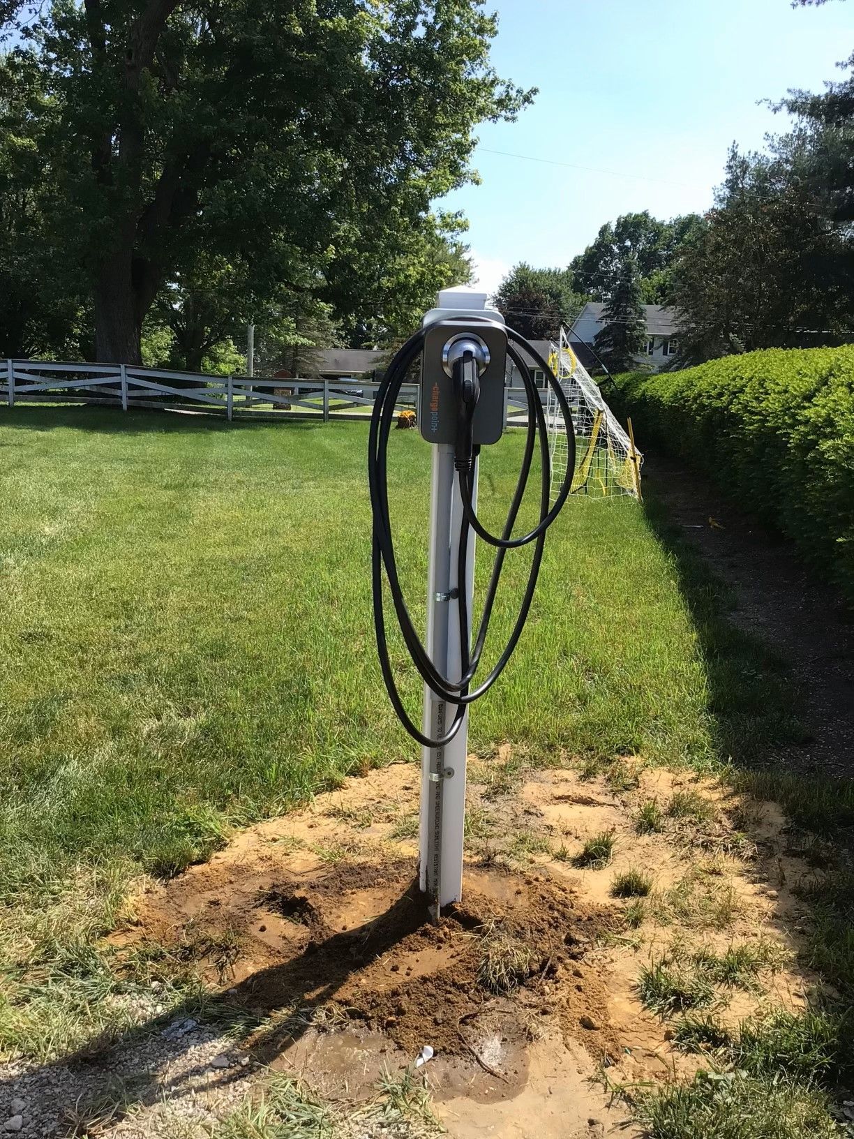 A pole with a cord attached to it is in the middle of a grassy field.