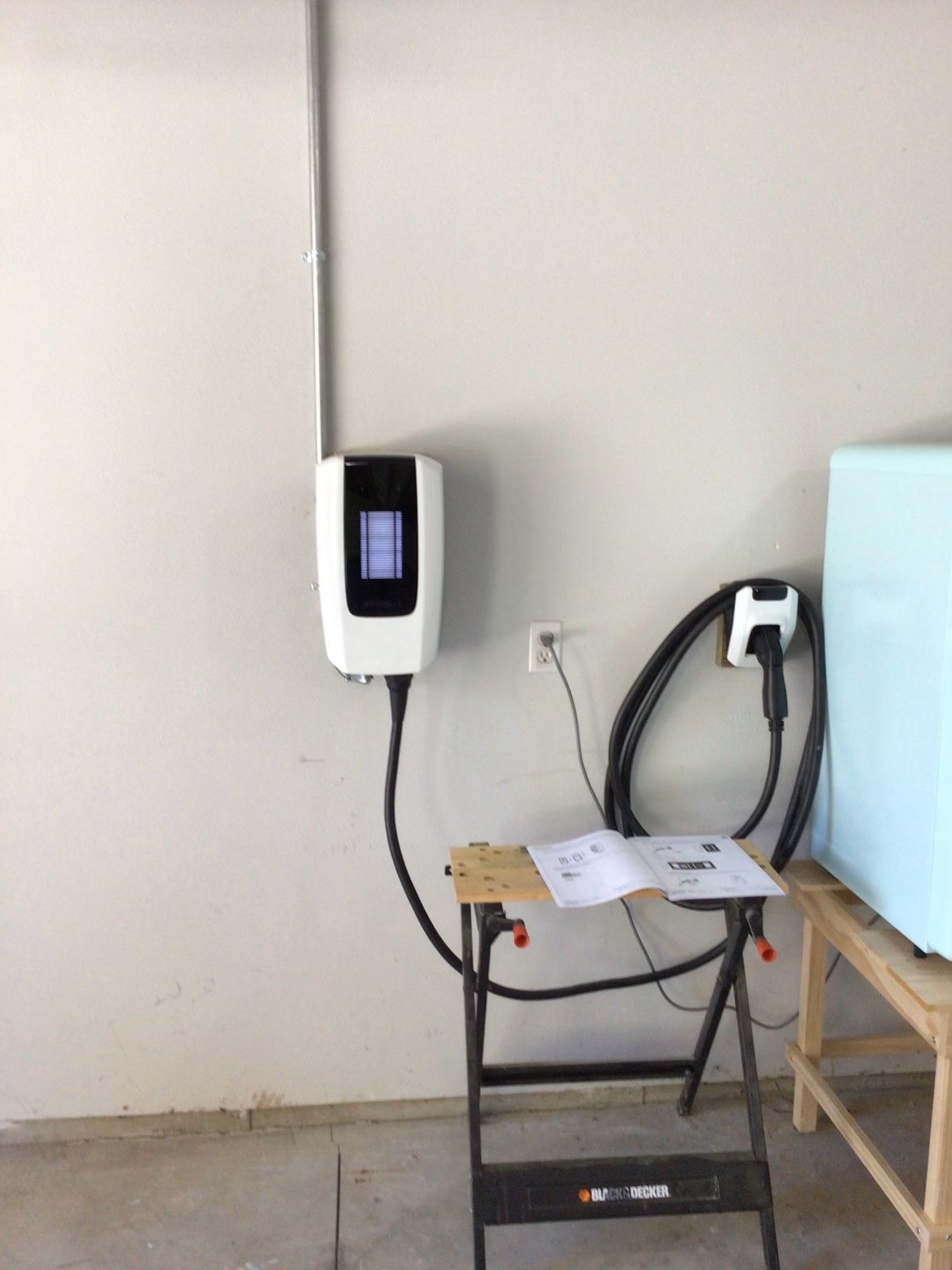A charging station is connected to a wall in a garage