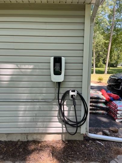 A tesla charging station is attached to the side of a house.