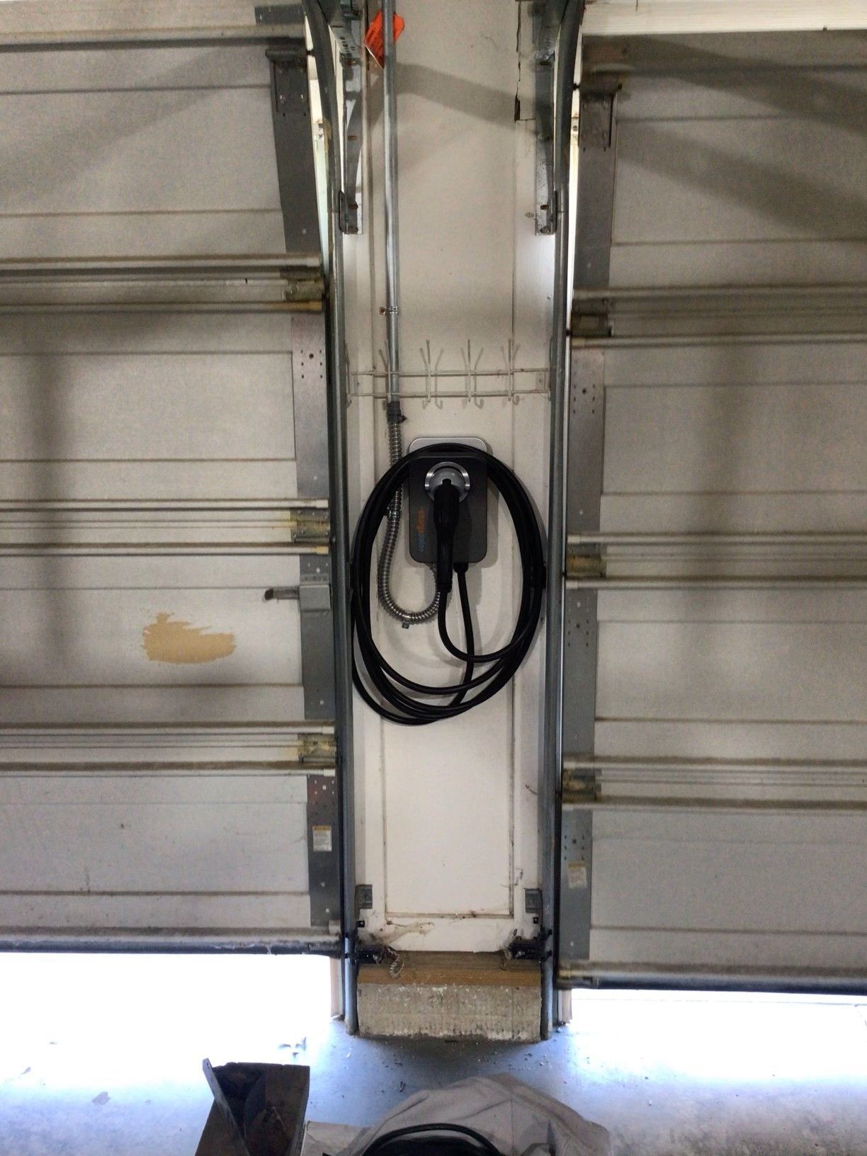 A black cord is hanging from the side of a garage door.