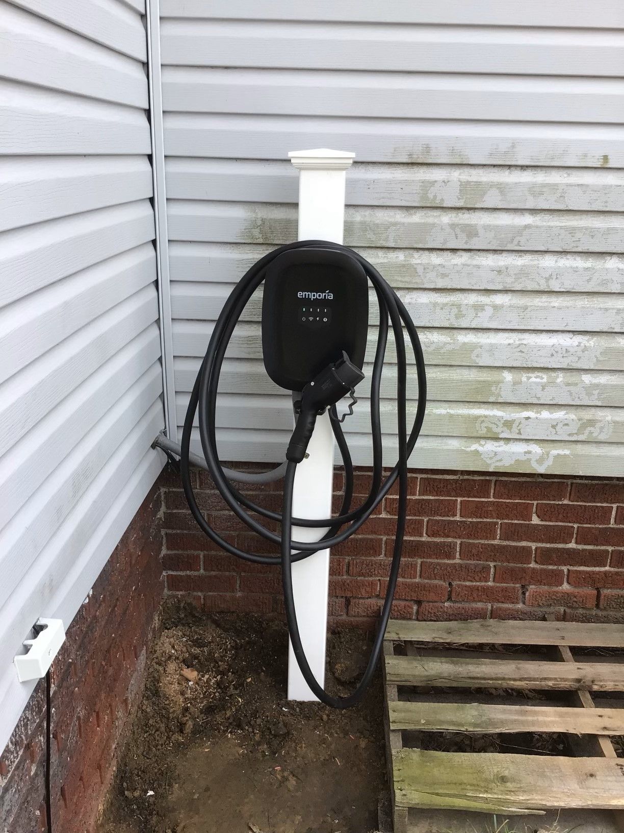 A tesla charging station is attached to the side of a house.