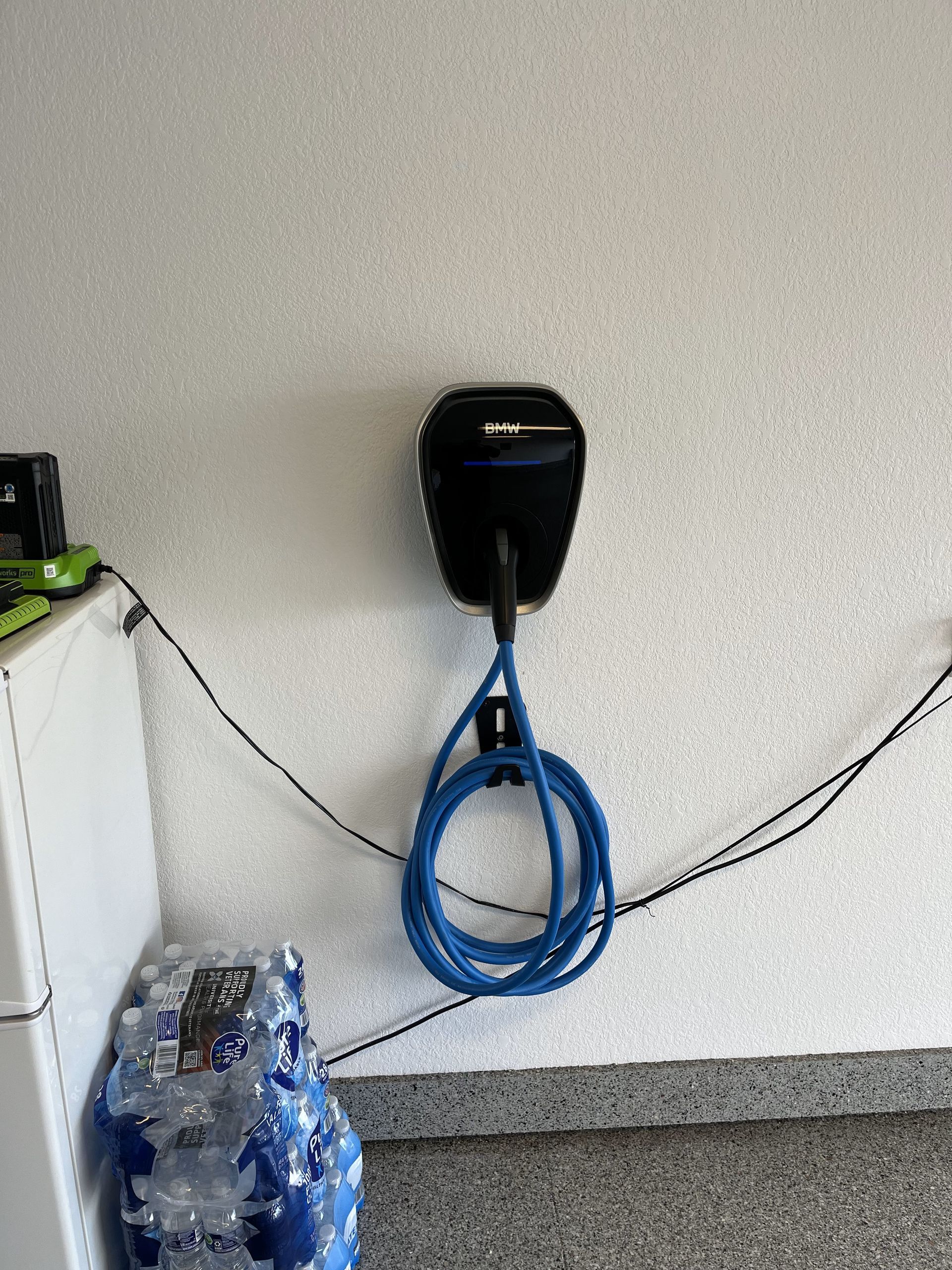 A blue cord is hanging from a wall next to a bottle of water.