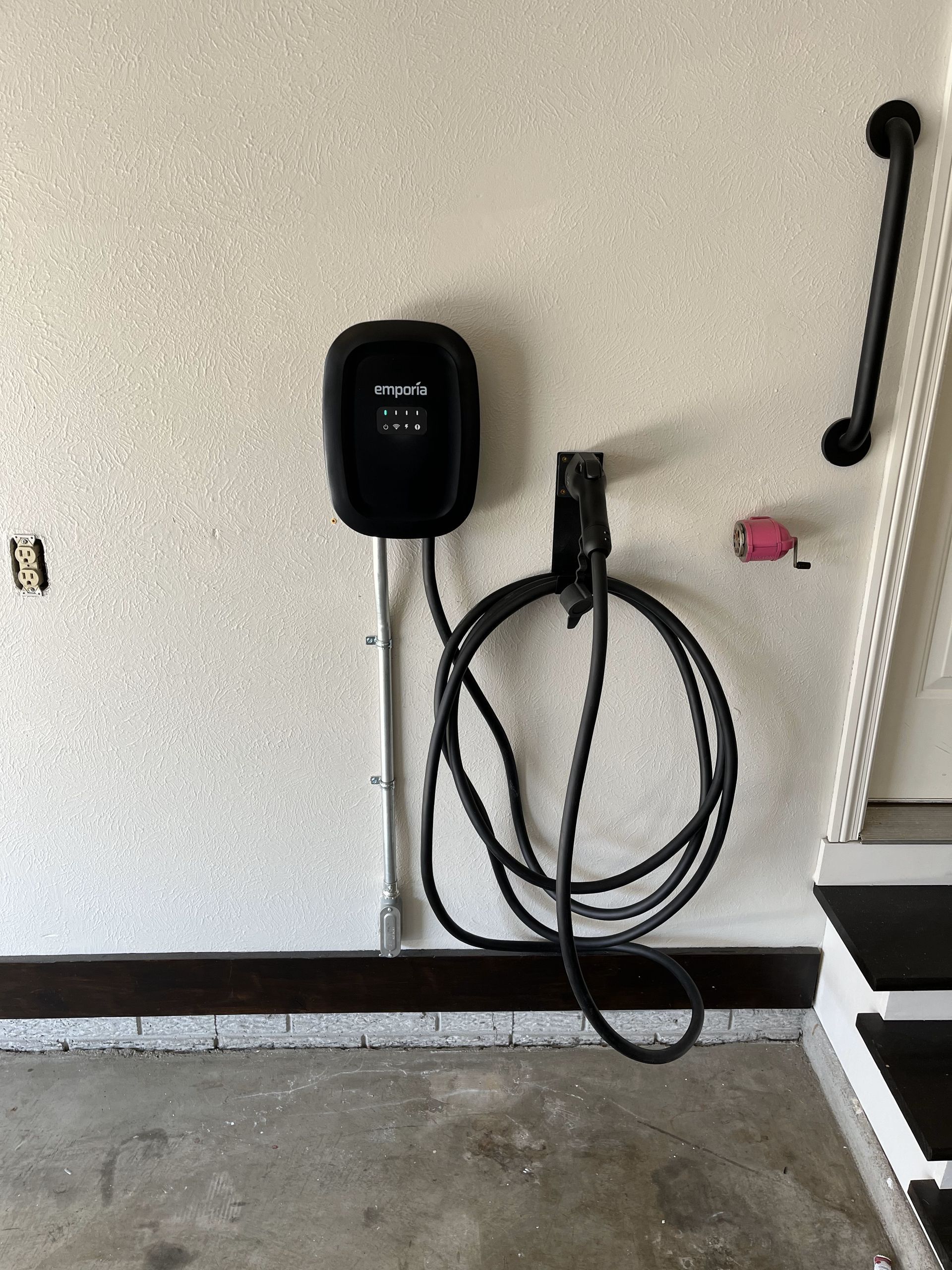 An electric car charger is attached to a wall in a garage.