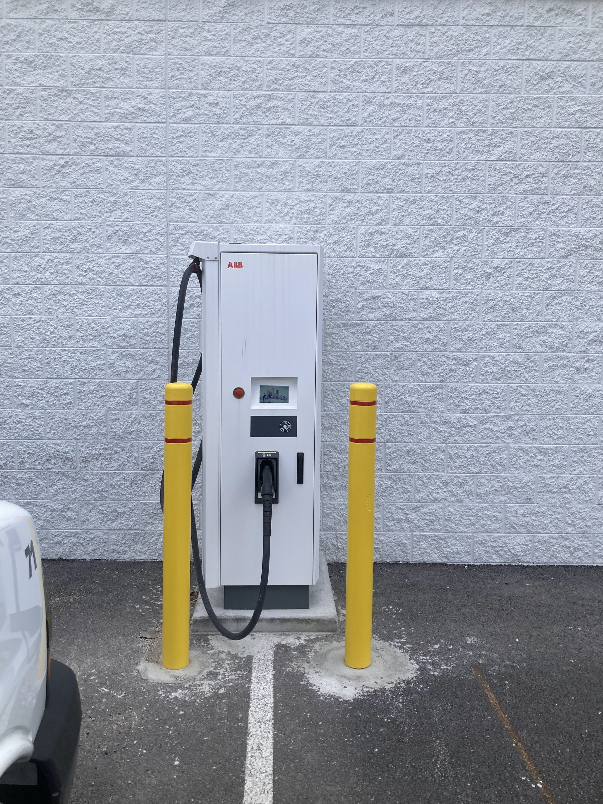 A white car is parked in front of a charging station