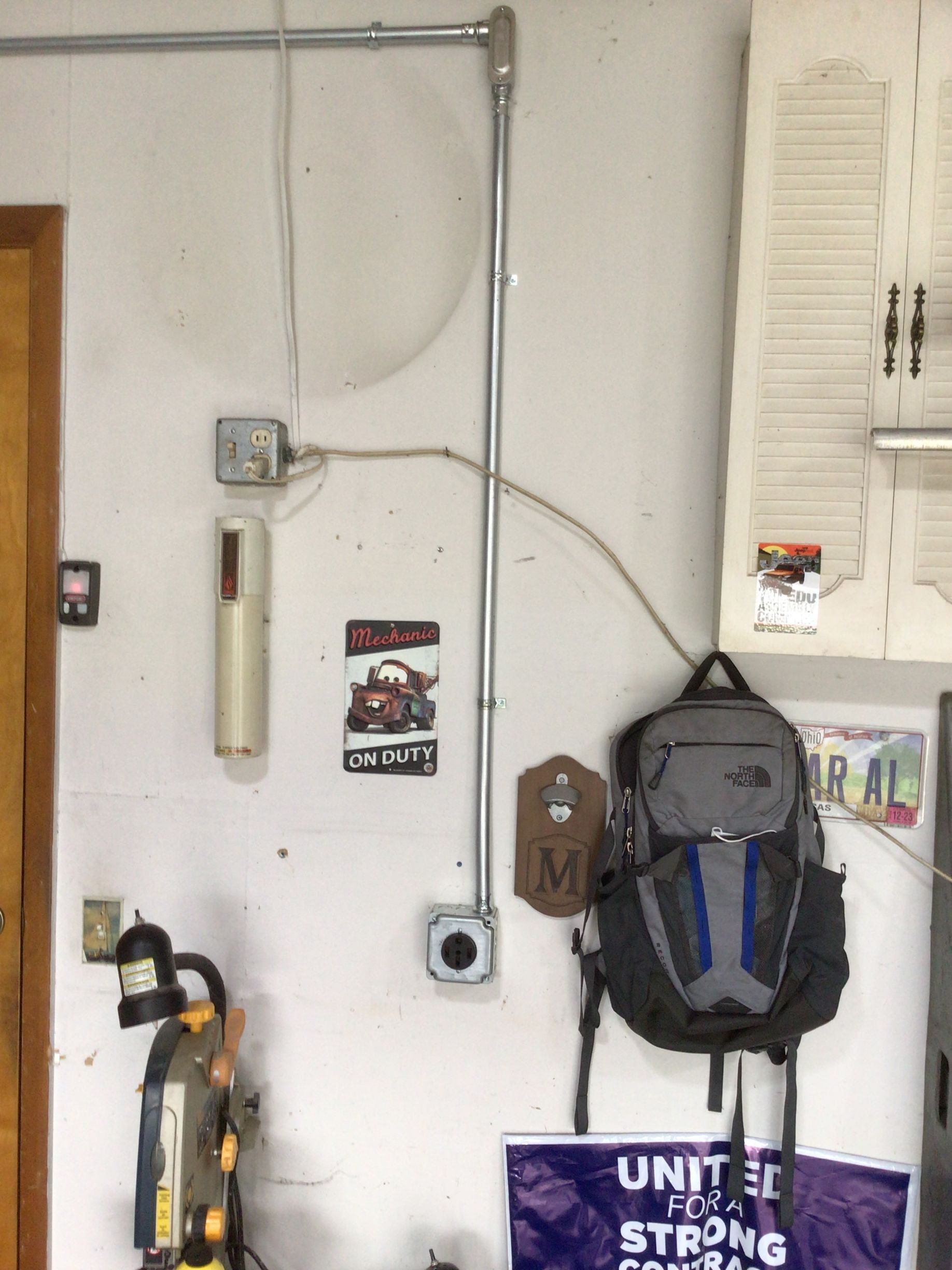 A backpack is hanging on a wall next to a sign that says united strong
