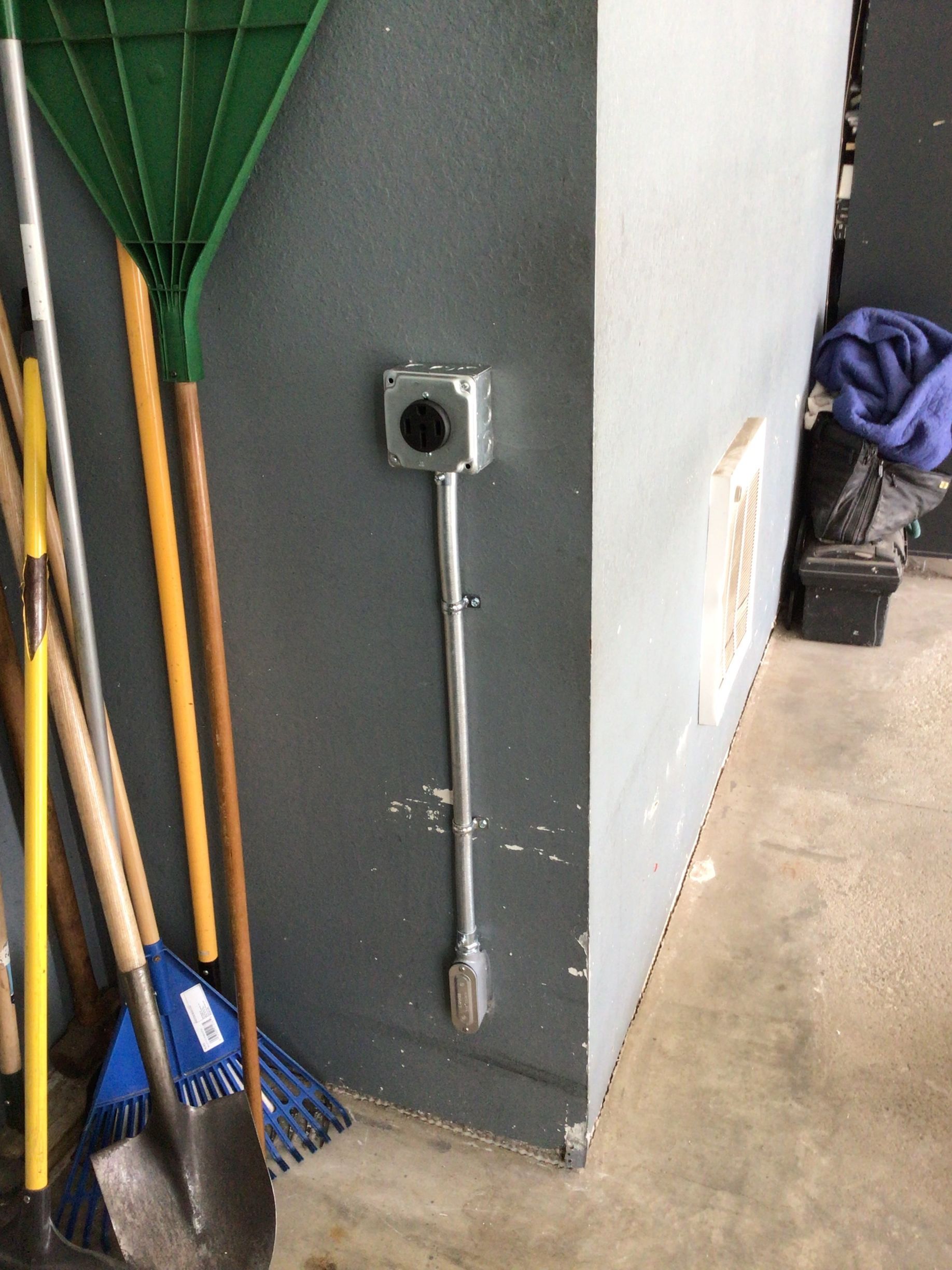 A bunch of brooms and shovels are sitting next to a wall.