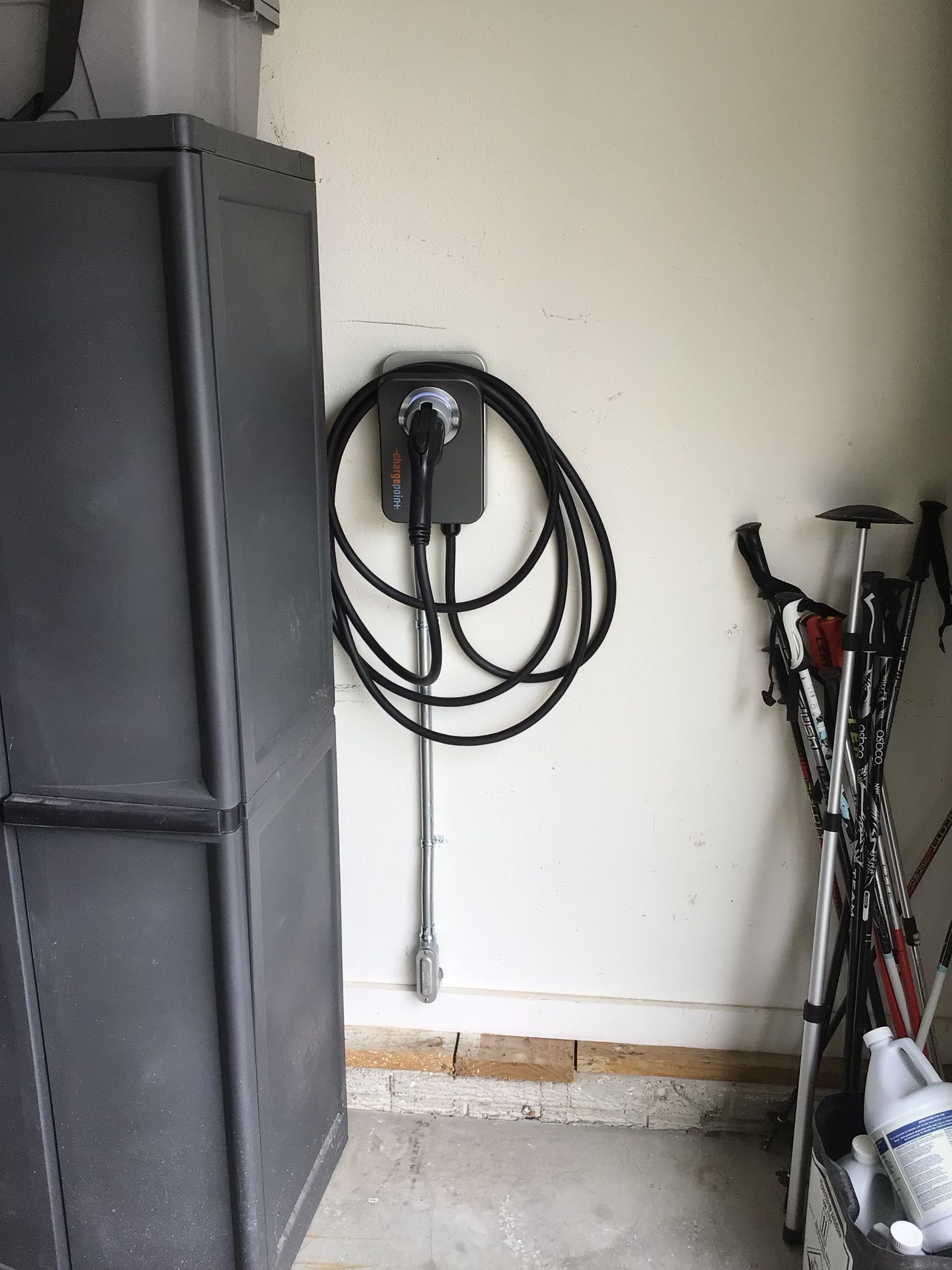 A charging station is hanging on a wall in a garage.