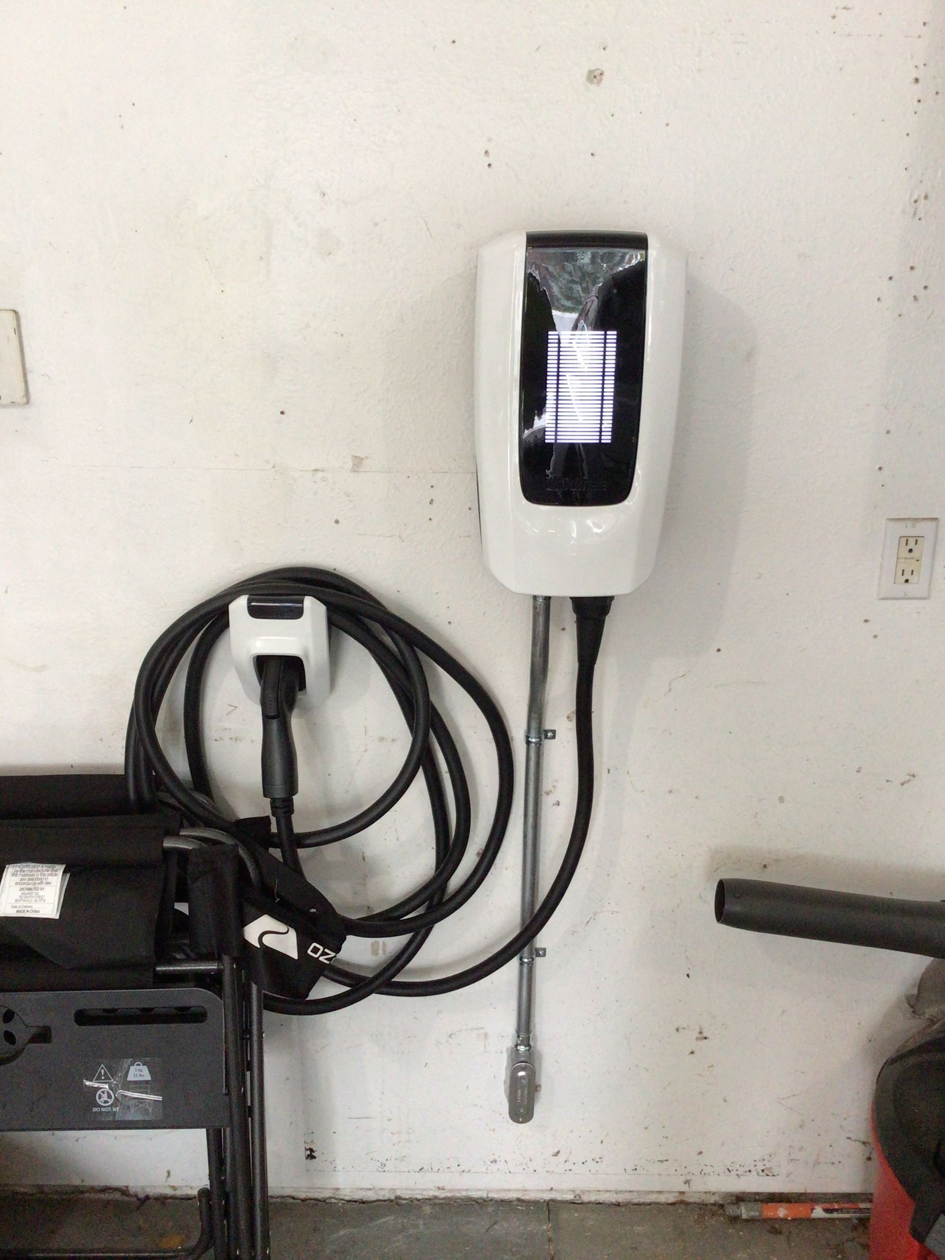 A charging station is hanging on a wall in a garage.