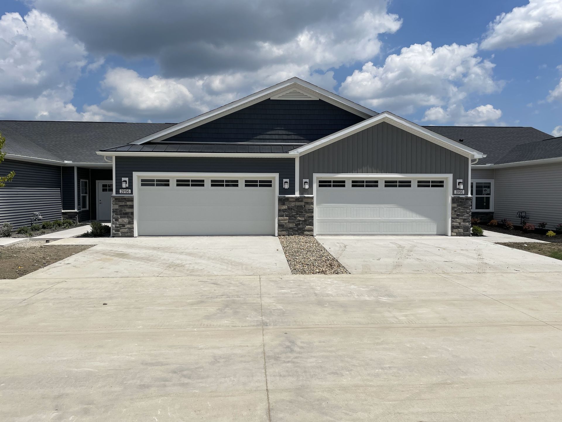 A house with two garage doors and a concrete driveway in front of it.