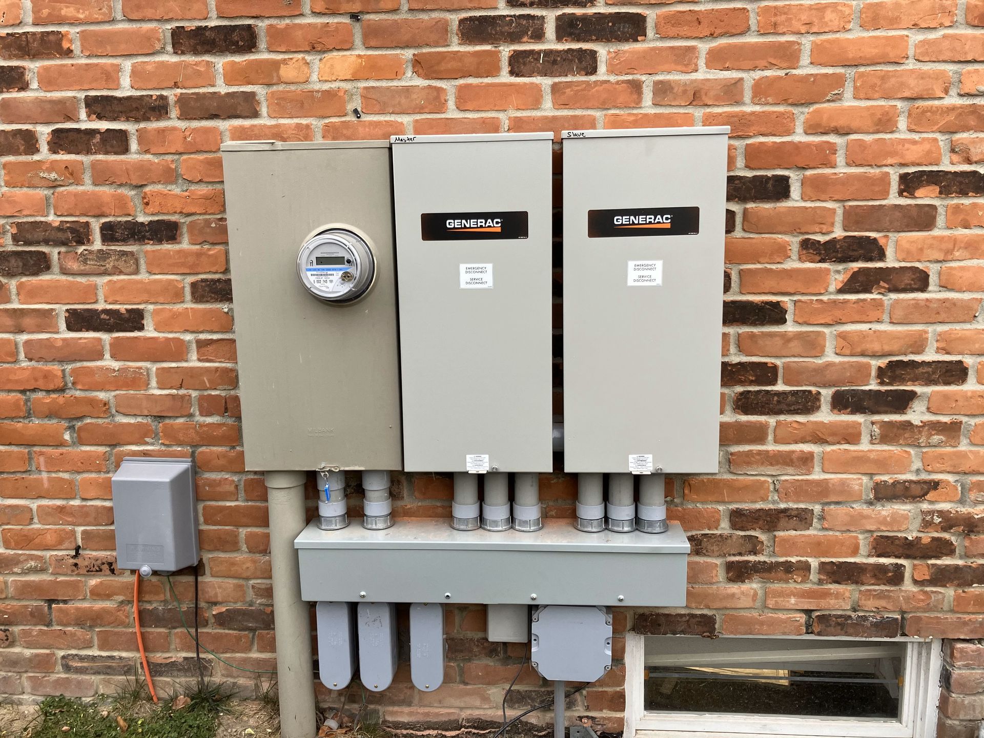A brick wall with electrical boxes and a meter on it.