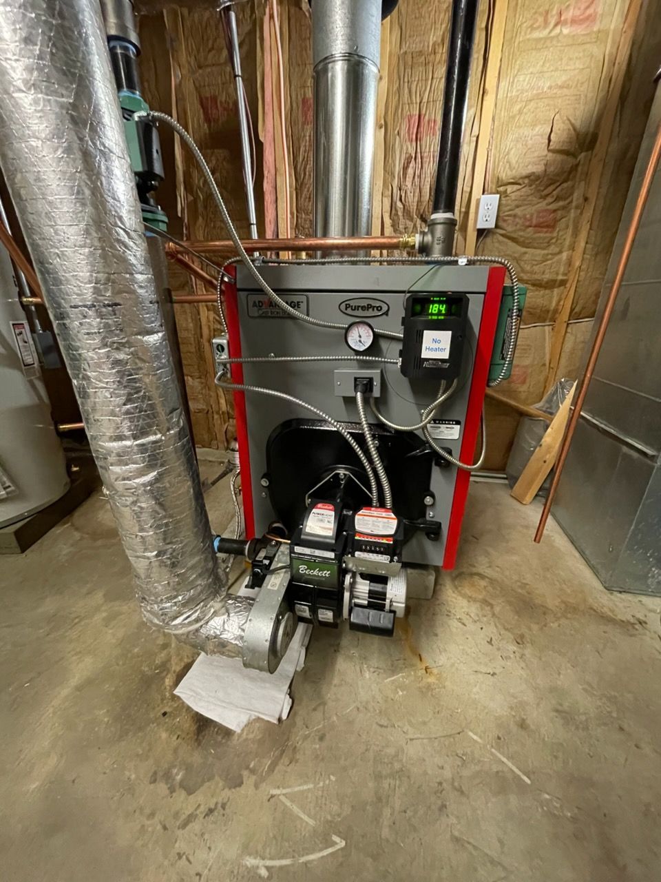 Oil furnace in a utility room with silver vent pipe.
