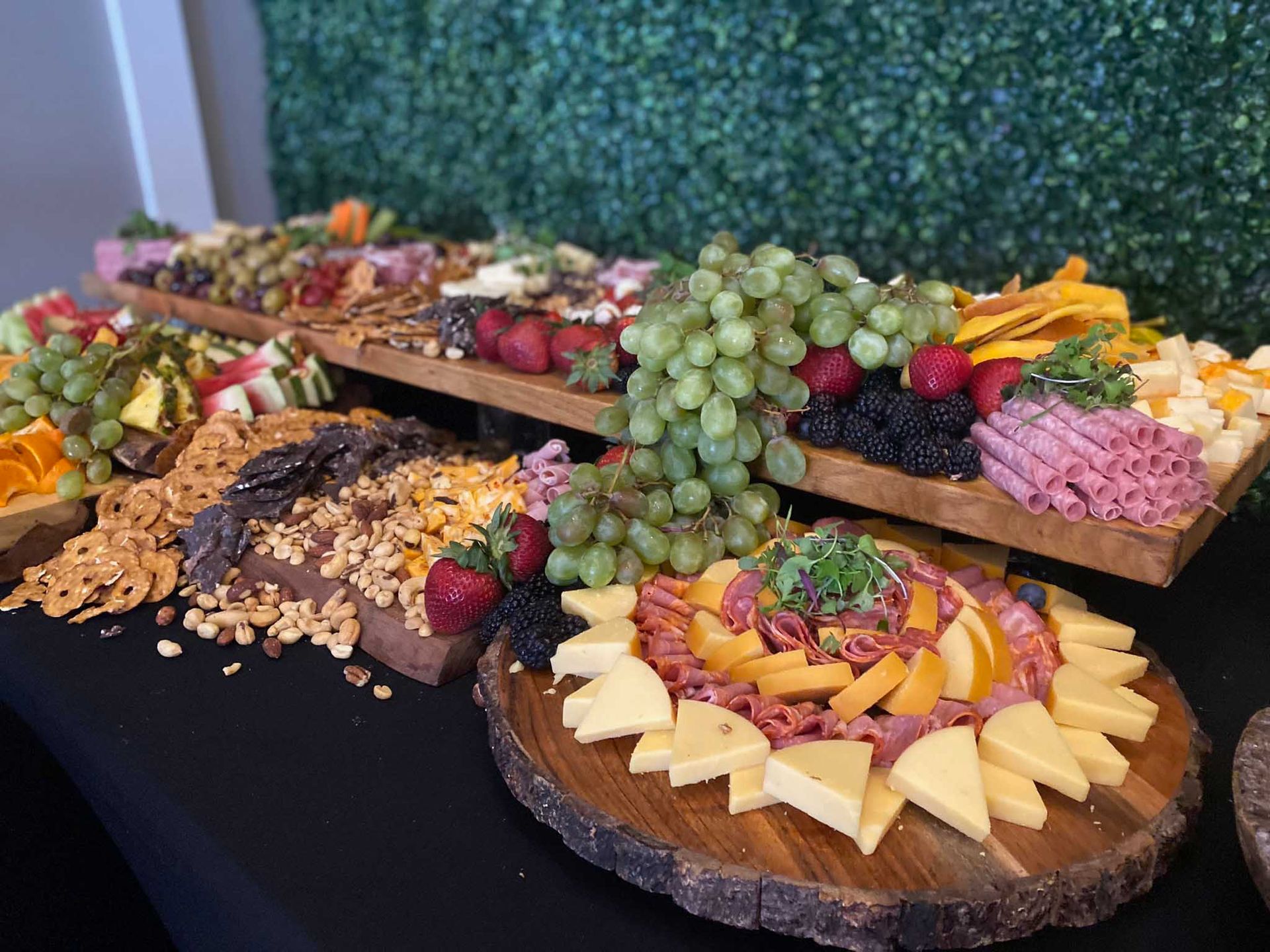 Charcuterie boards with various cheeses, meats, crackers, and fruit arranged on wooden platters.