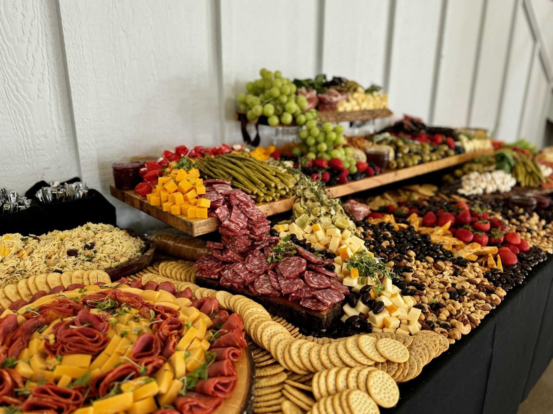 A lavish charcuterie spread with various cheeses, meats, crackers, fruits, and vegetables on a buffet table.